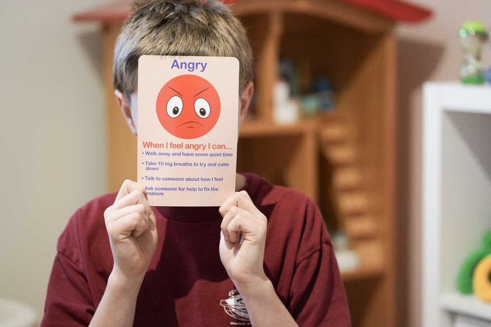 A child holding an emotions card during a session